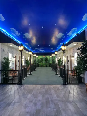 A calming hallway with a sky-themed ceiling leads to private memory care rooms.
